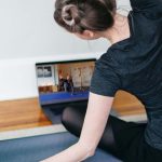 Frau mit Yogathek auf Laptop übt Yoga auf ihrer Yogamatte
